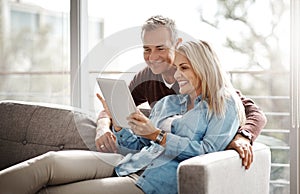 They do screen time as a couple. Shot of a mature couple using a digital tablet while relaxing together on the sofa at