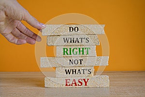 Do what is right not what is easy. Red words on the beautiful brick blocks on beautiful orange background. Businessman hand.