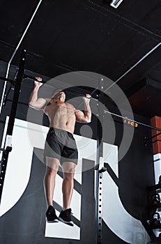 Do the work, reap the benefits. Shot of a young man lifting doing pull ups at a gym.