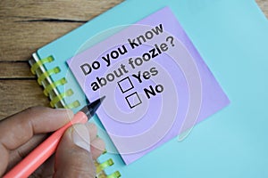 Do you know about foozle write on sticky notes  on Wooden Table. A person is answering question concept