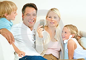 Do you remember this. a woman showing her husband her phone while their two children sit next to them.