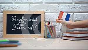 Do you speak French written on board, hand putting France flag in box, language