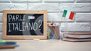 Do you speak Italian written on board, hand putting Italy flag in box, language
