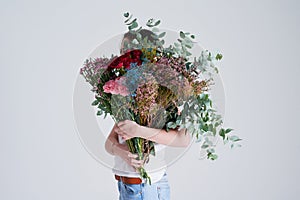 Do you suppose shes a wildflower. Studio shot of an unrecognizable woman covering her face with flowers against a grey