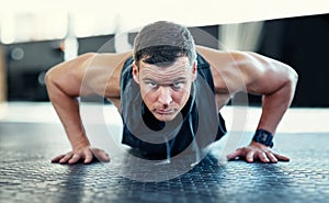 Do your push ups and dont give up. a young man doing push ups in a gym.