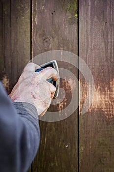 Do it yourself, closeup hand with a electric sander on wooden bo