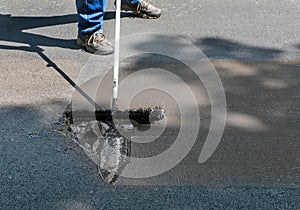 Spreading asphalt sealant on driveway photo