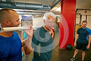 Do it for yourself. a senior man doing pvc pipe exercises with the assistance of his trainer.