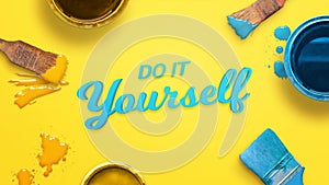 Do it yourself text surrounded with color brushes and boxes and a few drops of color on yellow surface