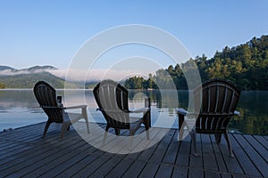 Adirondack Chairs on a Dock on a lake in the early morning photo