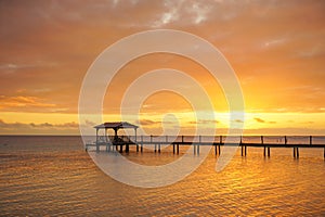 A dock leads out over a lagoon at sunset on the island of Fakarava in French Polynesia photo