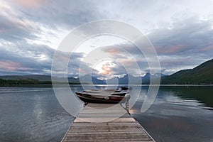 Dock over of lake Mcdonald surrounded by mountains during sunset