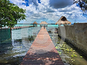 Dock with palm roof above a multicolor lake in Bacalar, Mexico.