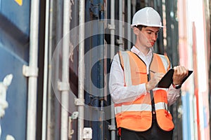 Dock worker man in safety vest take note on tablet.  Checking defect in shipping container yard. Import and export product.