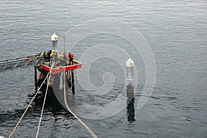 Dock workers drag a boat dock lines from a cruise ship to the dock to be tied up