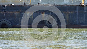 Docked barge with huge hanging tires on a river shore on a sunny day