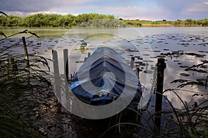 Docked boat by the shore of a river in the italian countryside