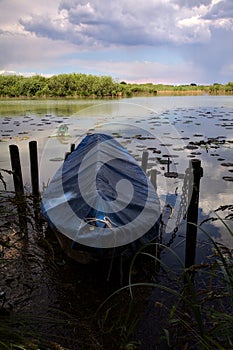 Docked boat by the shore of a river in the italian countryside