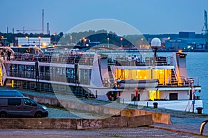 Docked cruise ship at the harbor of antwerp city, lighted city scenery by night, quay of Antwerpen, Belgium