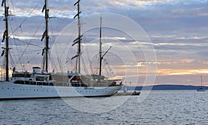 Docked old sailing ship anchored to a pier at sunset