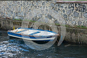 Docked Rowboat by Stone Wall