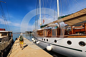 Docked ship in port. Docking on the pier in the Mediterranean. Yacht parked at dock. Tourist with backpack walking on the pier