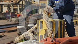 Dockworker unmooring big vessel in dock