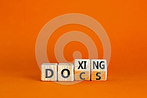 Docs or doxing symbol. Concept words Docs Doxing on wooden block. Beautiful orange table orange background. Business docs or