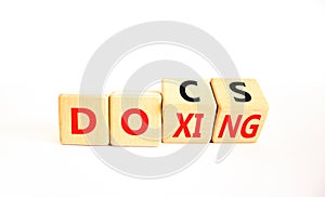 Docs or doxing symbol. Concept words Docs Doxing on wooden block. Beautiful white table white background. Business docs or doxing