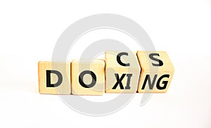 Docs or doxing symbol. Concept words Docs Doxing on wooden block. Beautiful white table white background. Business docs or doxing