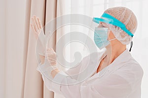 Doctor adjust the gloves to protect herself against covid-19 virus