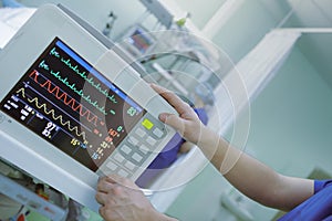 Doctor adjusting heart monitor connected to the severe patient in the intensive care unit