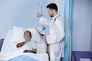 Doctor adjusting iv drip while patient lying on bed