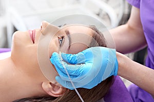 The doctor of aesthetic medicine performs a facial skin scraping treatment with a syringe.