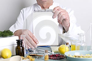 Doctor of alternative medicine holding blank notebook.Doctor`s workplace, natural medicines on the table.Free space for text photo