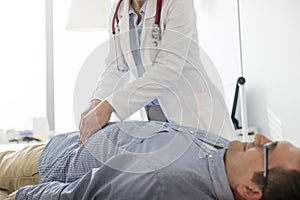 Doctor analyzing abdomen of patient in examination room at hospital