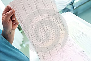 Doctor analyzing ECG chart in patient ward