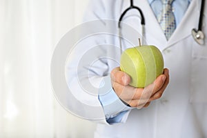 Doctor with apple and stethoscope, close up
