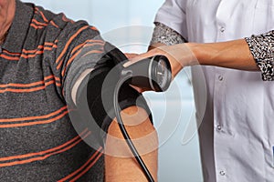 Doctor applies cuff for blood pressure measurement photo