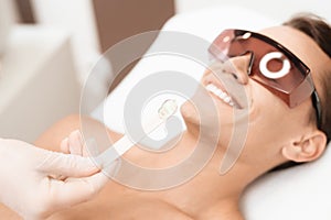 The doctor applies an epilation gel on the man`s face. The man laughs, because he is ticklish.