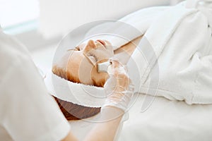 Doctor applies hydro gel mask on the woman before making laser treatment.