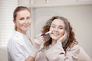 Doctor applies peeling mask for happy woman with smile use facial treatment on skin face in spa beauty salon