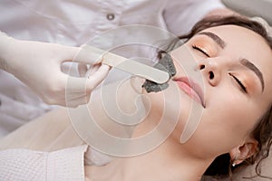 Doctor applies peeling mask for woman skin face in spa beauty salon