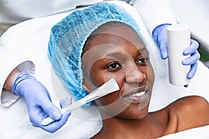 Doctor is applying with brush mask on woman in spa salon