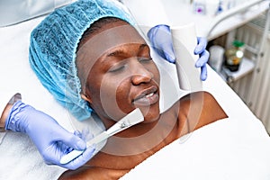 Doctor is applying with brush mask on woman in spa salon