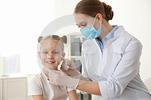 Doctor applying cream onto skin of girl with chickenpox in clinic. Varicella zoster virus