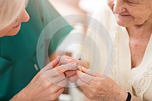 Doctor applying hearing aid to senior woman`s ear