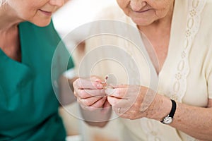 Doctor applying hearing aid to senior woman`s ear