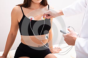 Doctor Applying Holter Heart Monitor On Woman`s Body In Clinic photo
