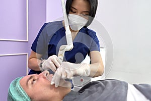 Doctor applying laser to perfom a beauty treatment to a patient in a clinic